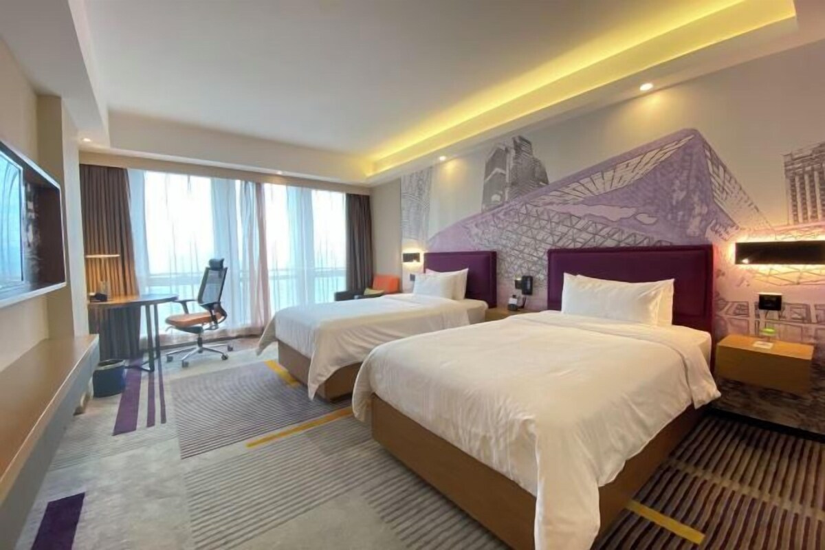 Habitación de hotel con dos camas, un escritorio y una silla.