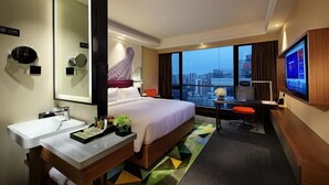 A hotel room with a bed, a desk, a TV, a large mirror, and a city view. - Hampton by Hilton Guangzhou Zhujiang New Town (Guangzhou)