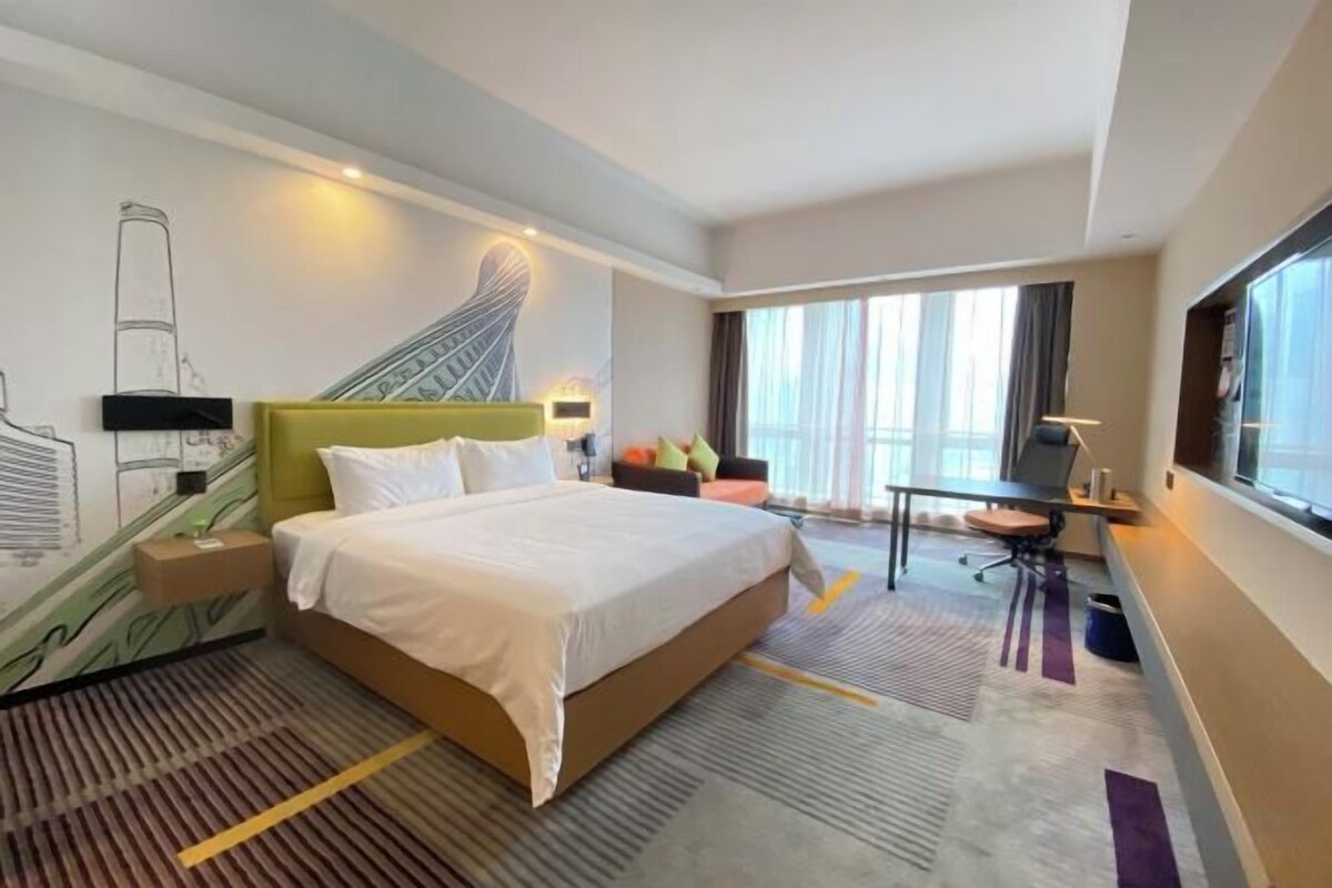 Habitación de hotel con una cama grande, un escritorio y vistas al exterior.