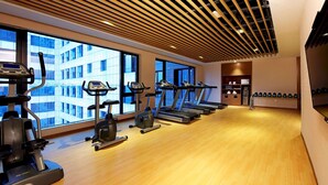A gym with treadmills, ellipticals, and a weight bench. - Hampton by Hilton Guangzhou Zhujiang New Town (Guangzhou)