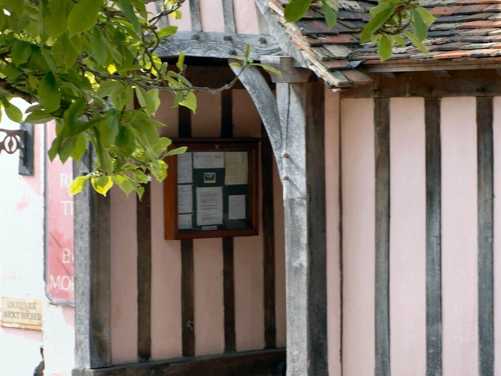 A building with a traditional architectural style, featuring a wooden archway and a window with a notice board.