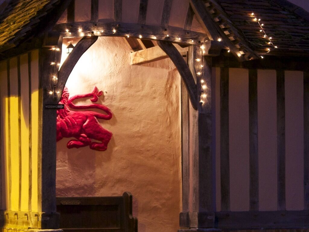 A rustic wooden structure with a thatched roof, illuminated by string lights.