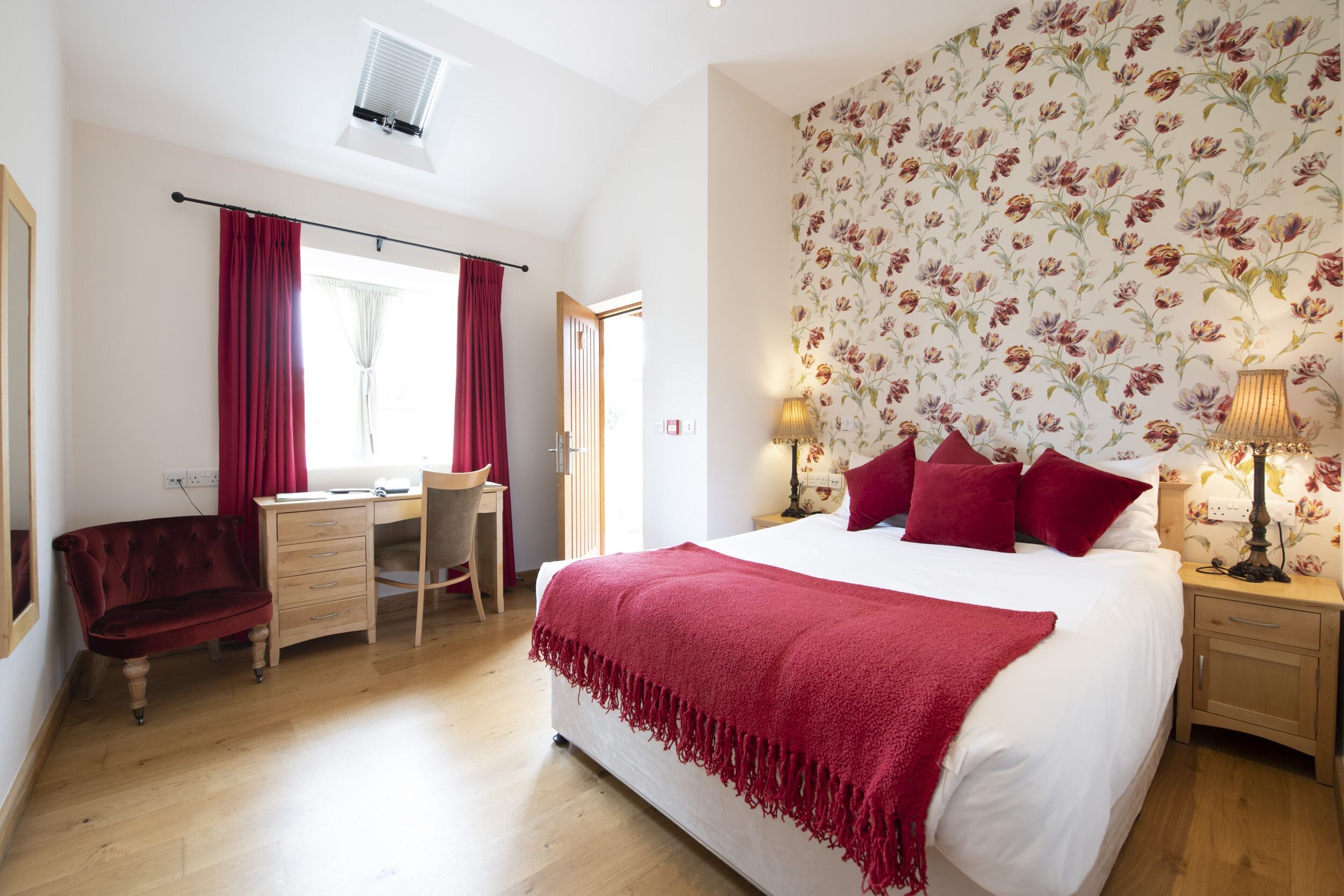 A bedroom with a large bed, a desk, a chair, and a wardrobe.