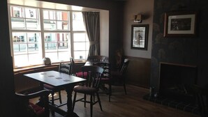 Un área de comedor con una mesa y sillas, una ventana con cortinas y una chimenea.