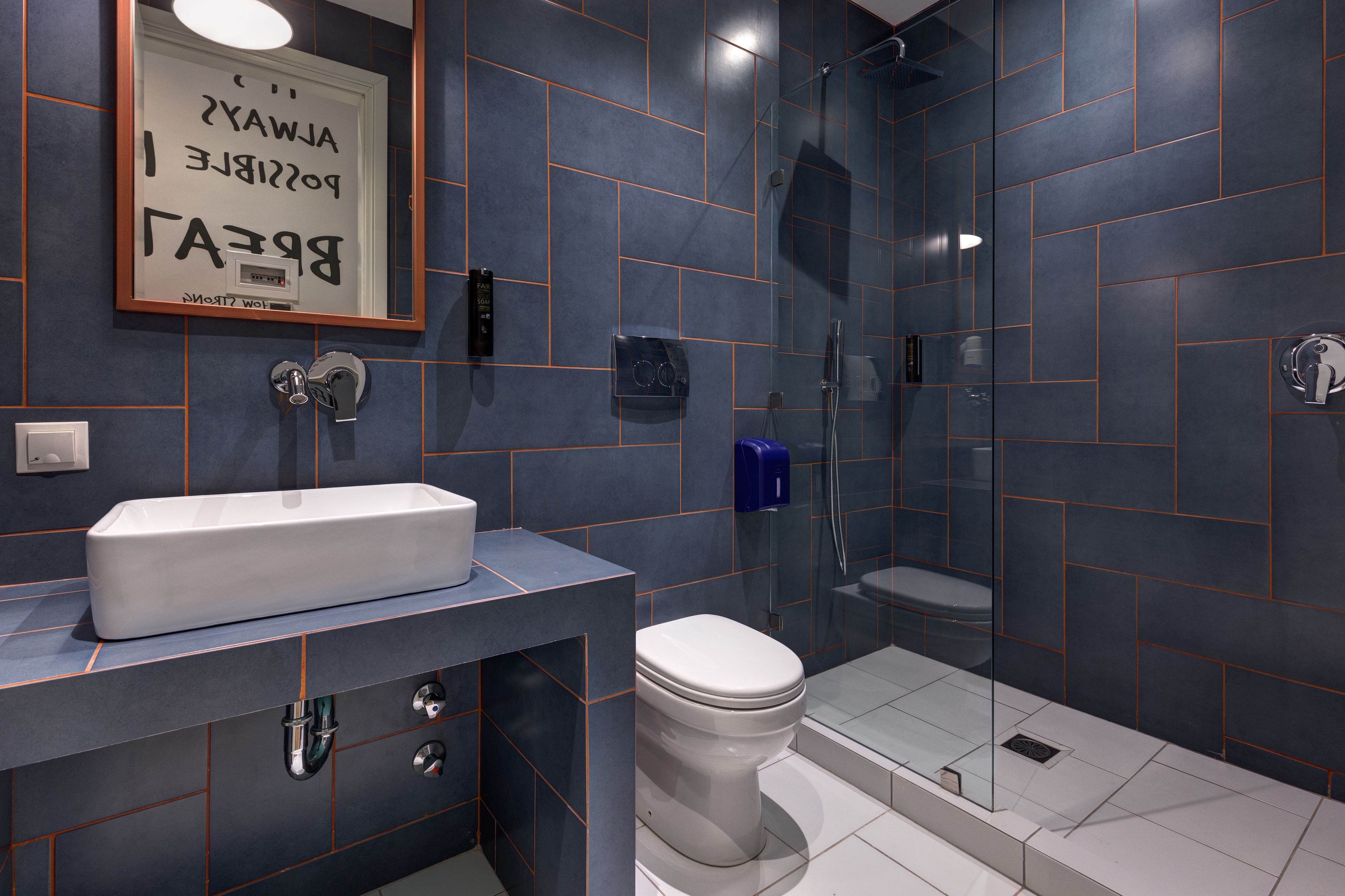 A modern bathroom with a rectangular sink, a toilet, and a glass-enclosed shower.