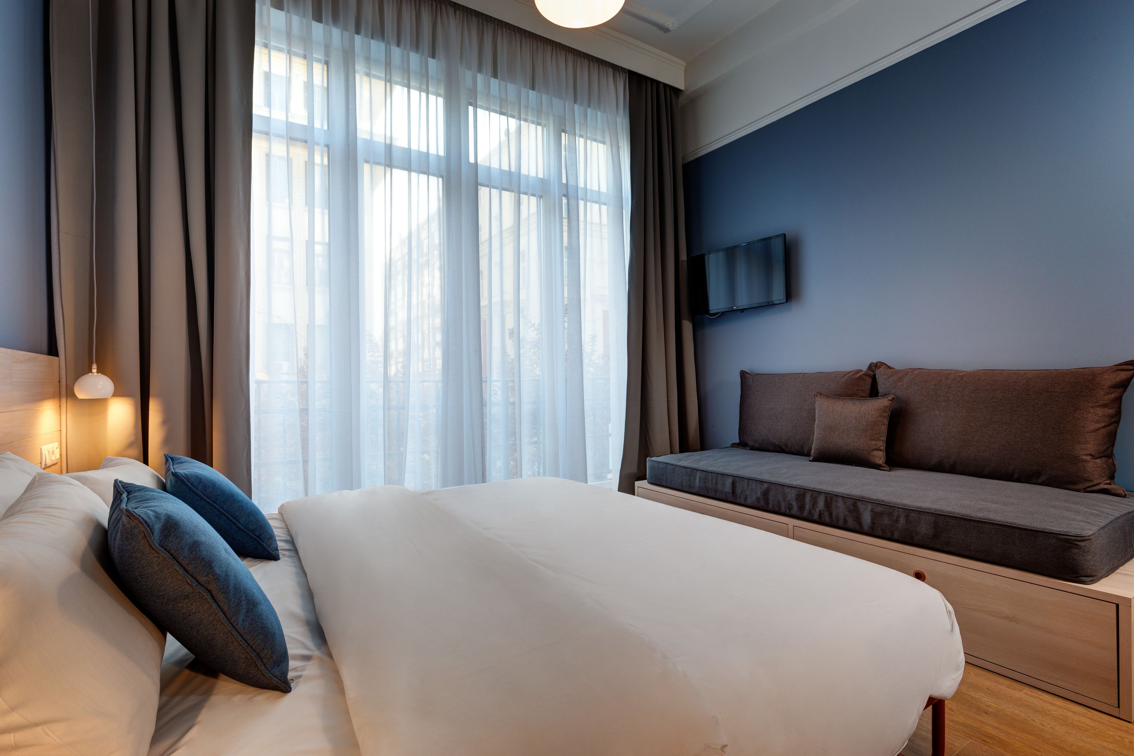 Une chambre d’hôtel moderne avec un grand lit, un canapé et un téléviseur fixé au mur.
