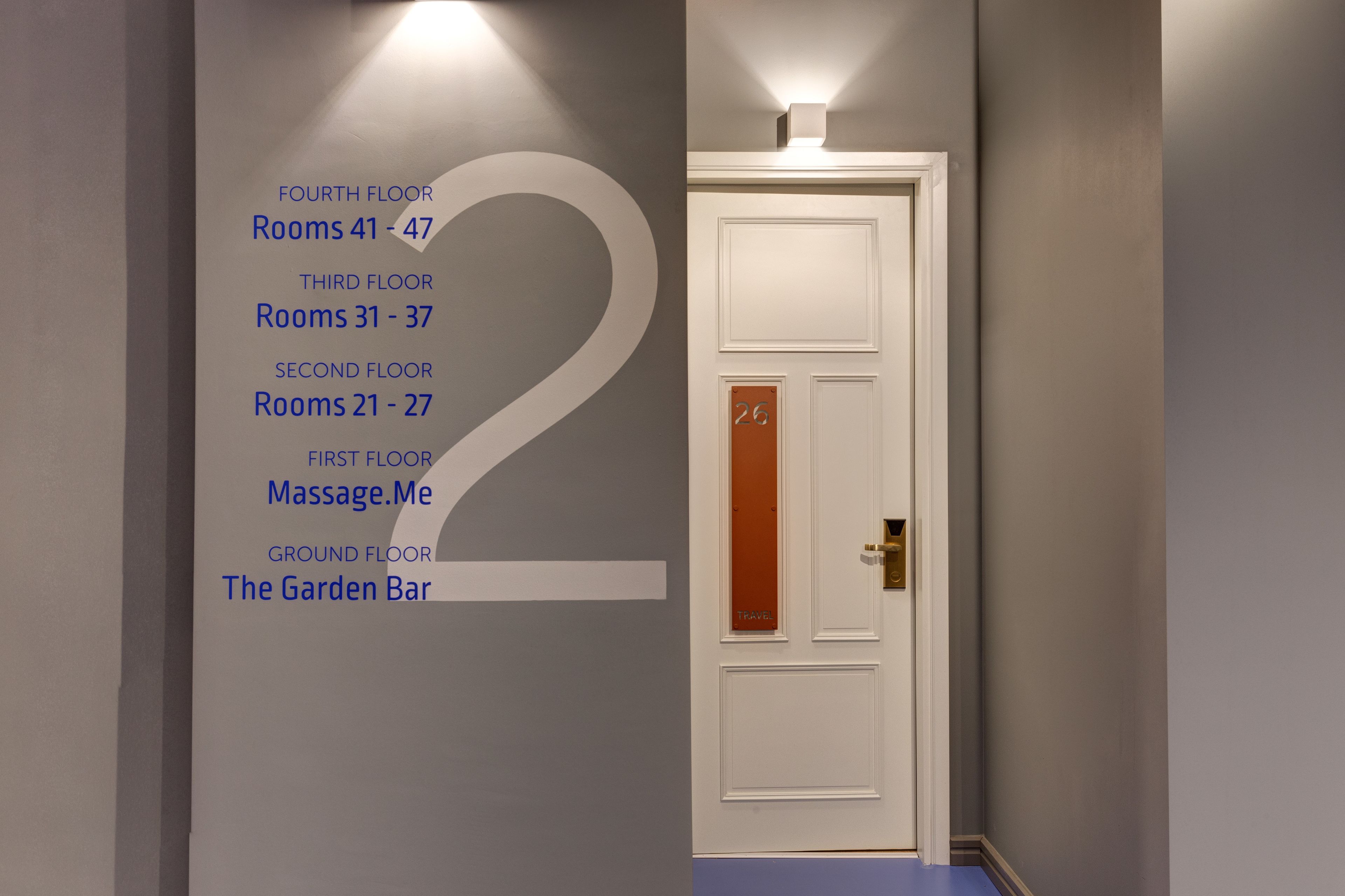A hallway with a large number '2' on the wall, indicating the second floor. There are signs for rooms on the fourth, third, and second floors, as well as a massage service on the first floor and a garden bar on the ground floor.