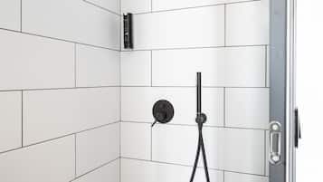 Une douche avec des carreaux blancs, un pommeau de douche à main et un robinet fixé au mur.