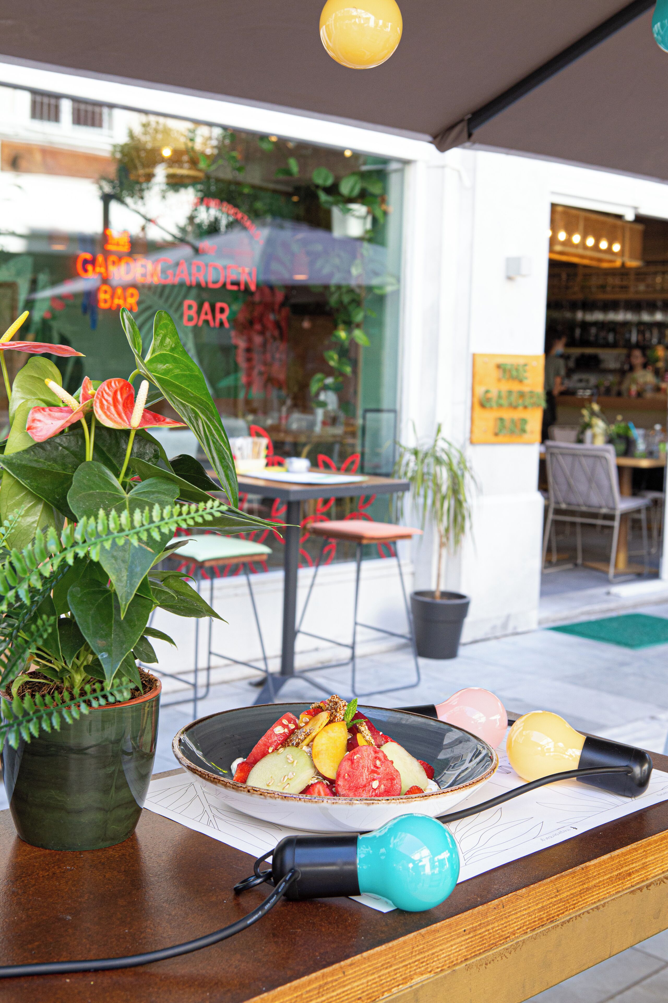 A restaurant with a garden theme, featuring outdoor seating and a variety of plants.