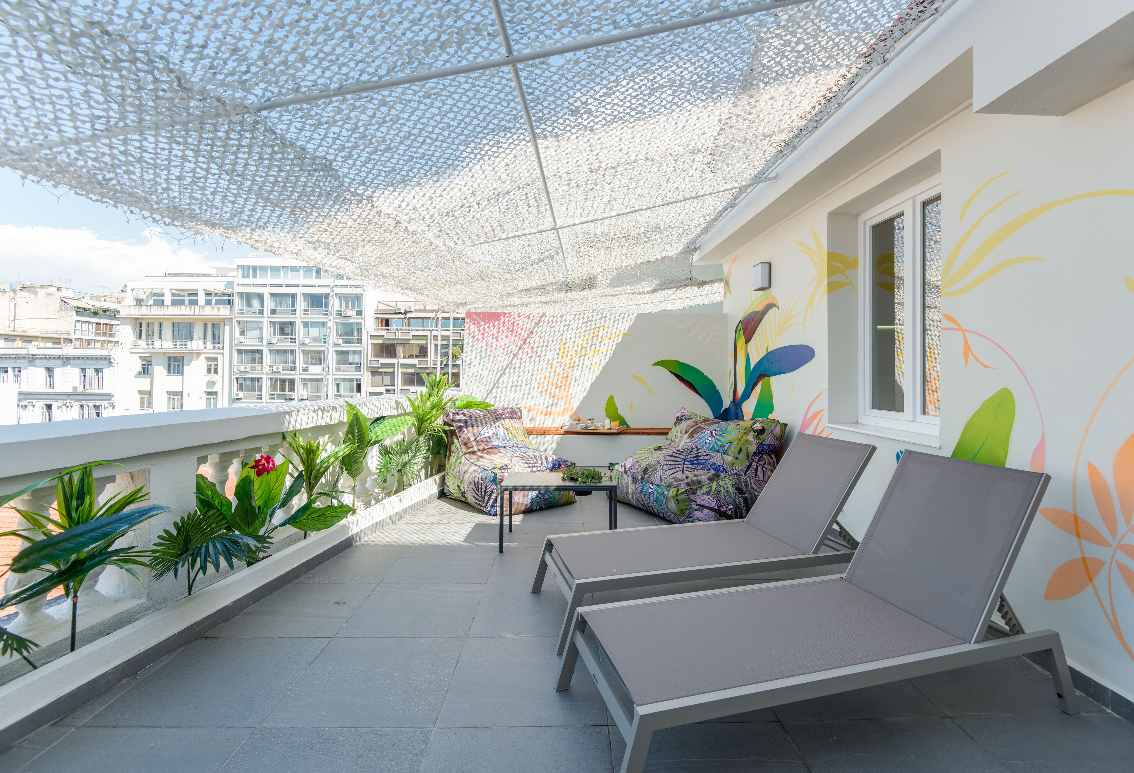 Un balcón con dos sillones, una mesita y un mural de pared colorido.