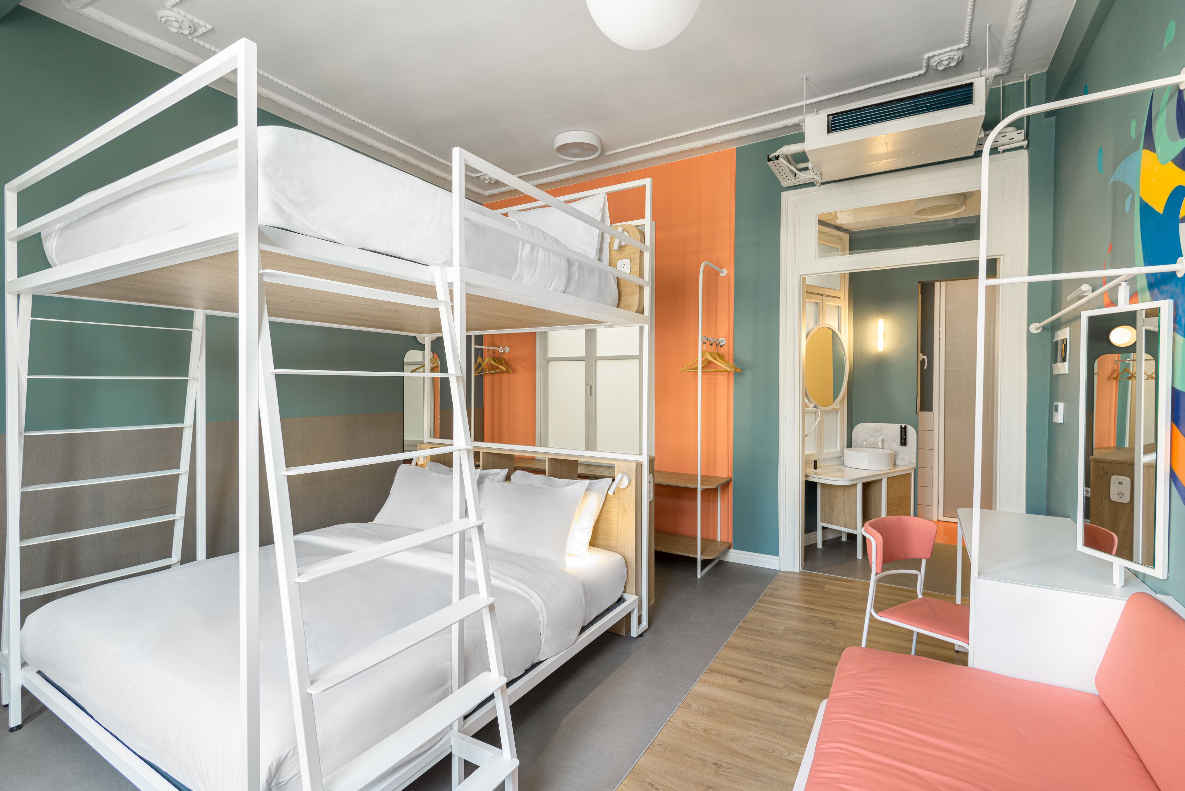 Une chambre avec un lit superposé, un bureau et une chaise, un miroir et une petite salle de bain.