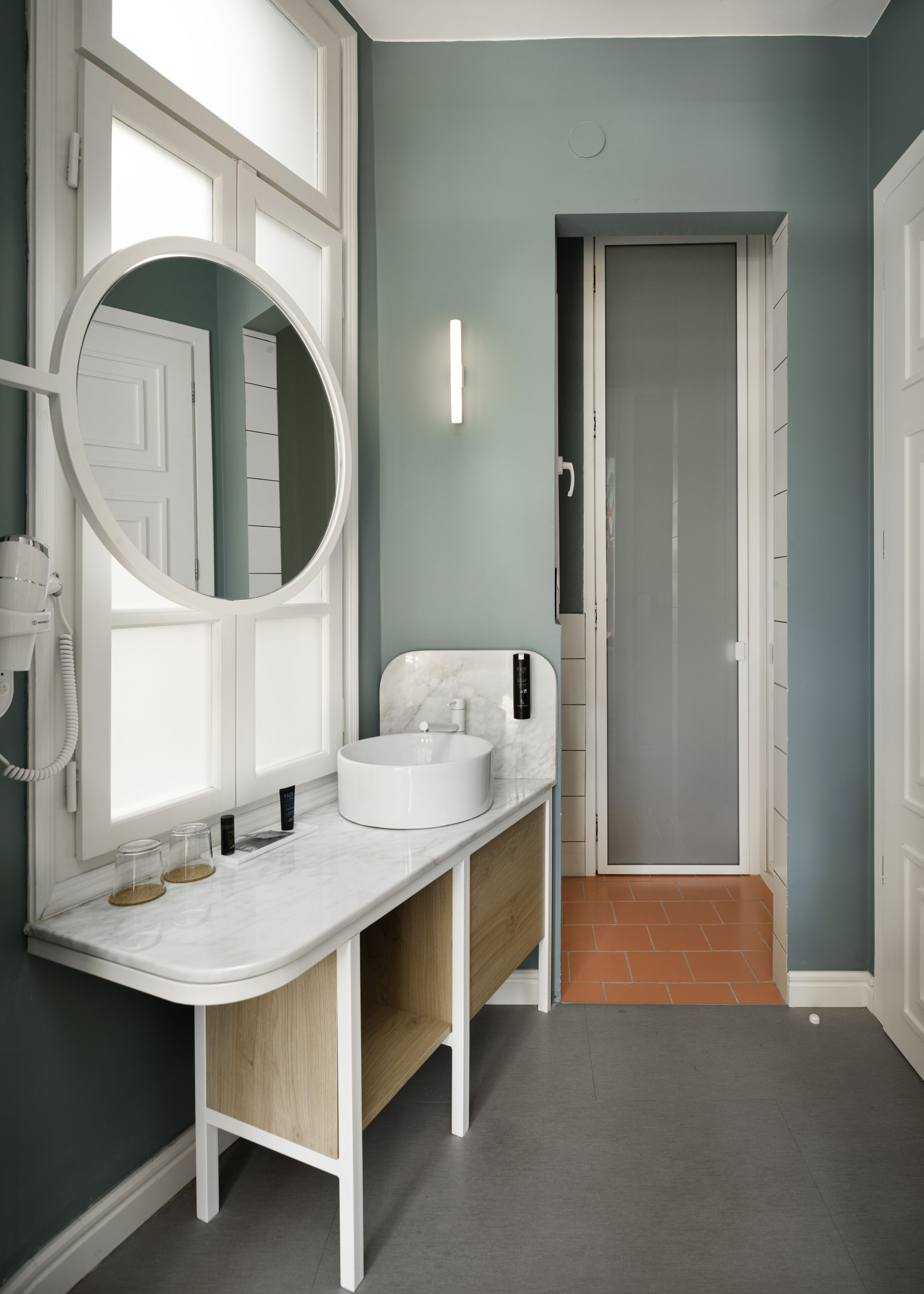 A bathroom with a white vanity, a round mirror, and a white sink.
