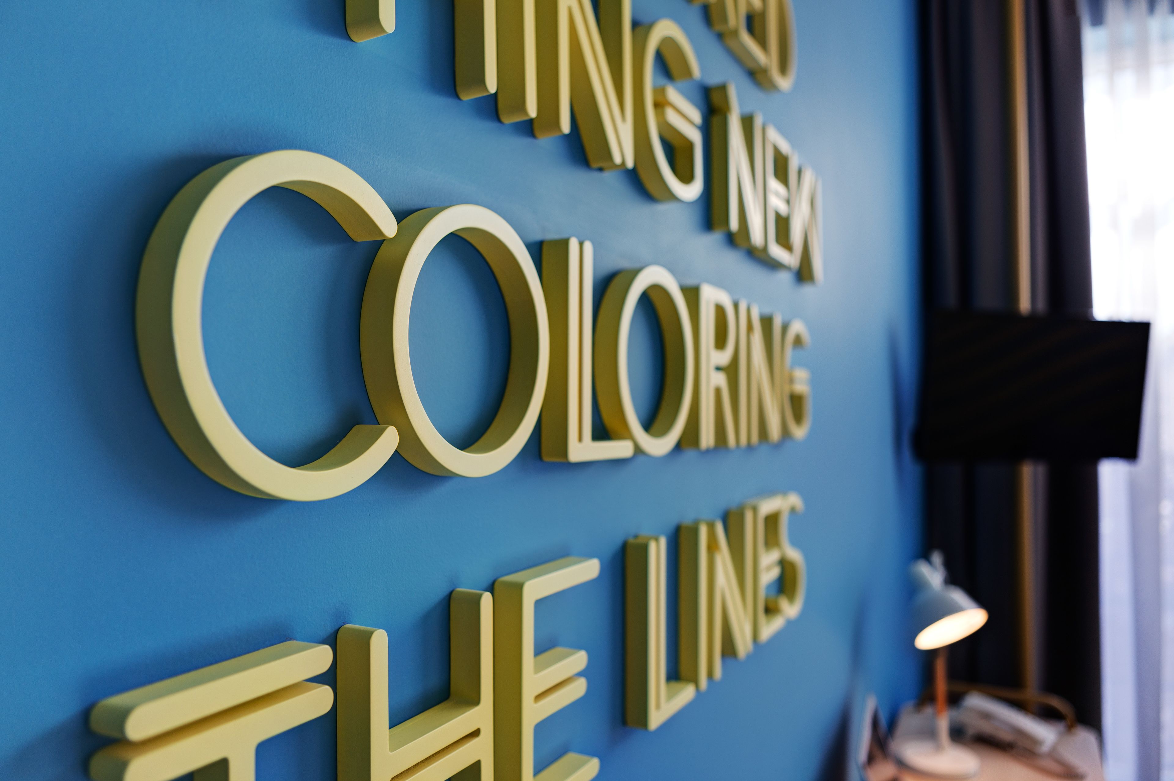 Un mur orné de grandes lettres en relief qui forment l’expression « COLORING THE LINES ».