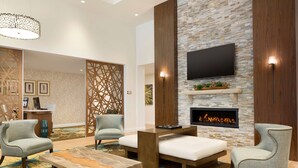 A modern living room with a fireplace, comfortable seating, and a flat-screen TV mounted on the wall. - Homewood Suites by Hilton Augusta (Augusta)