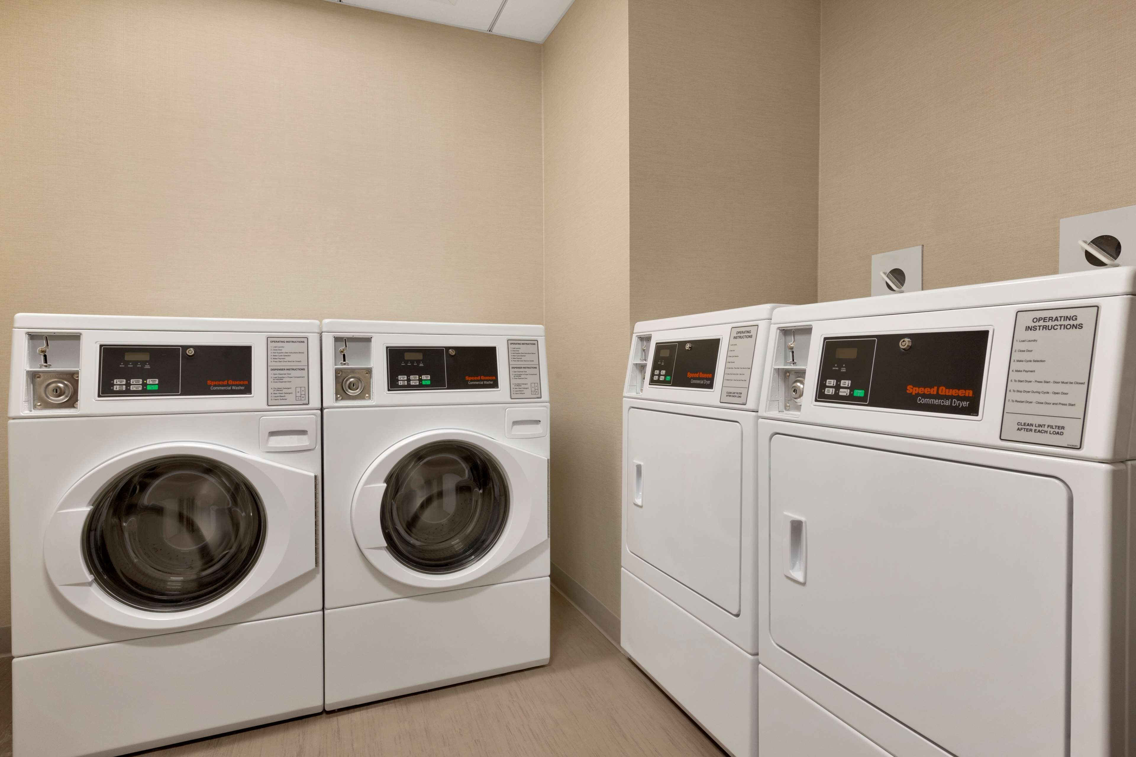 A laundry area with two front-loading washing machines and a dryer.