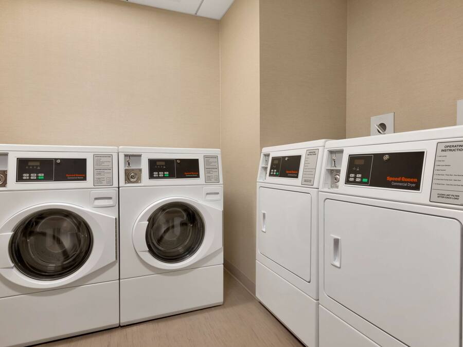 A laundry area with two front-loading washing machines and a dryer.