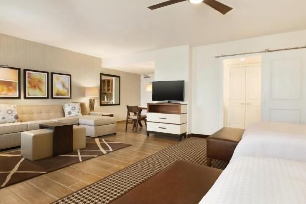 Una habitación de hotel con sofá, televisor, escritorio y cama.