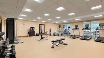 A well-lit gym with treadmills, elliptical machines, and free weights.