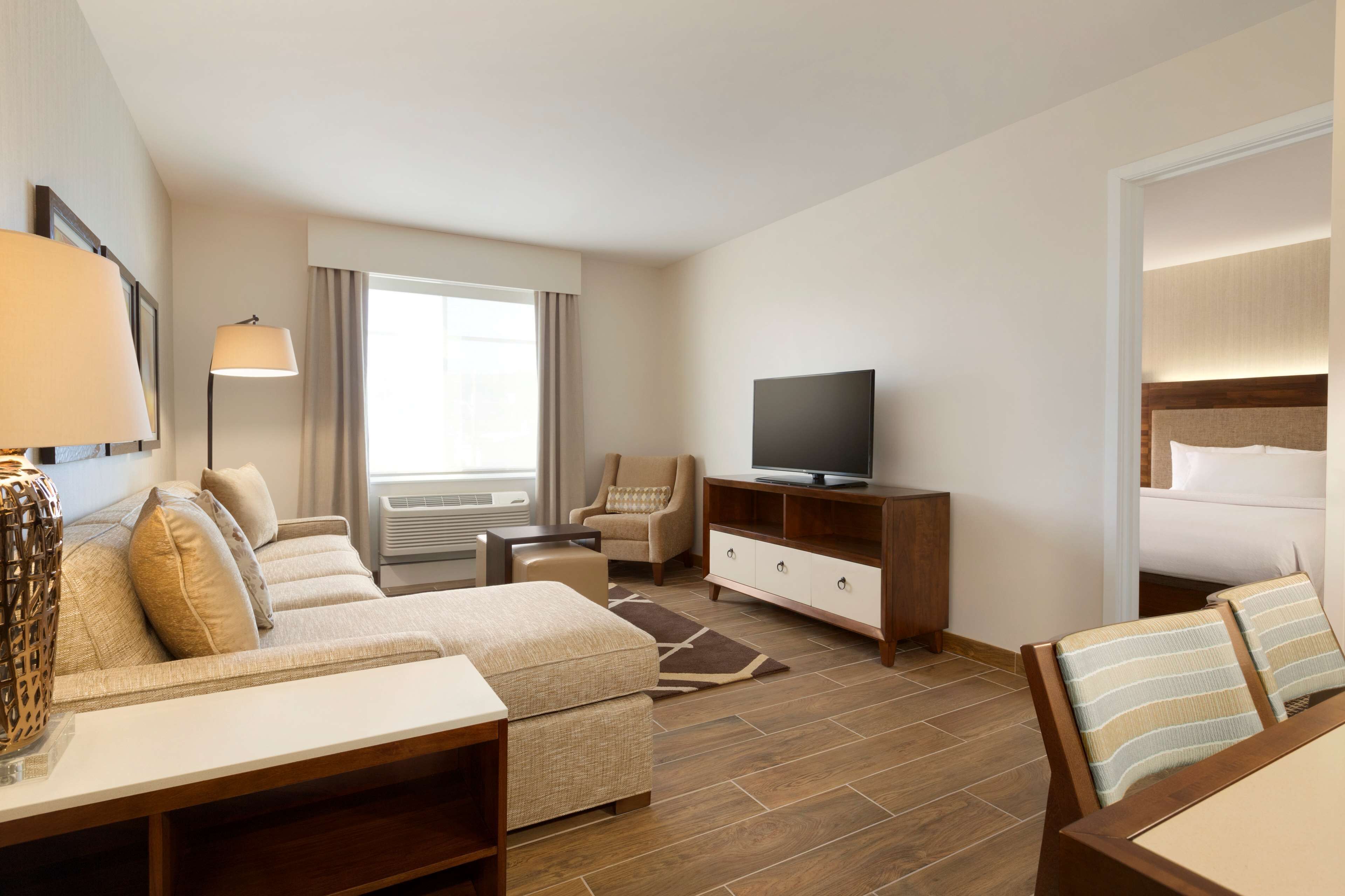 Una habitación de hotel con sofá, sillón, televisión y cama.