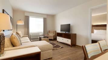 Una habitación de hotel con sofá, sillón, televisión y cama.