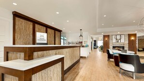 A hotel lobby with a reception desk, a fireplace, and seating area. - Homewood Suites by Hilton Augusta (Augusta)
