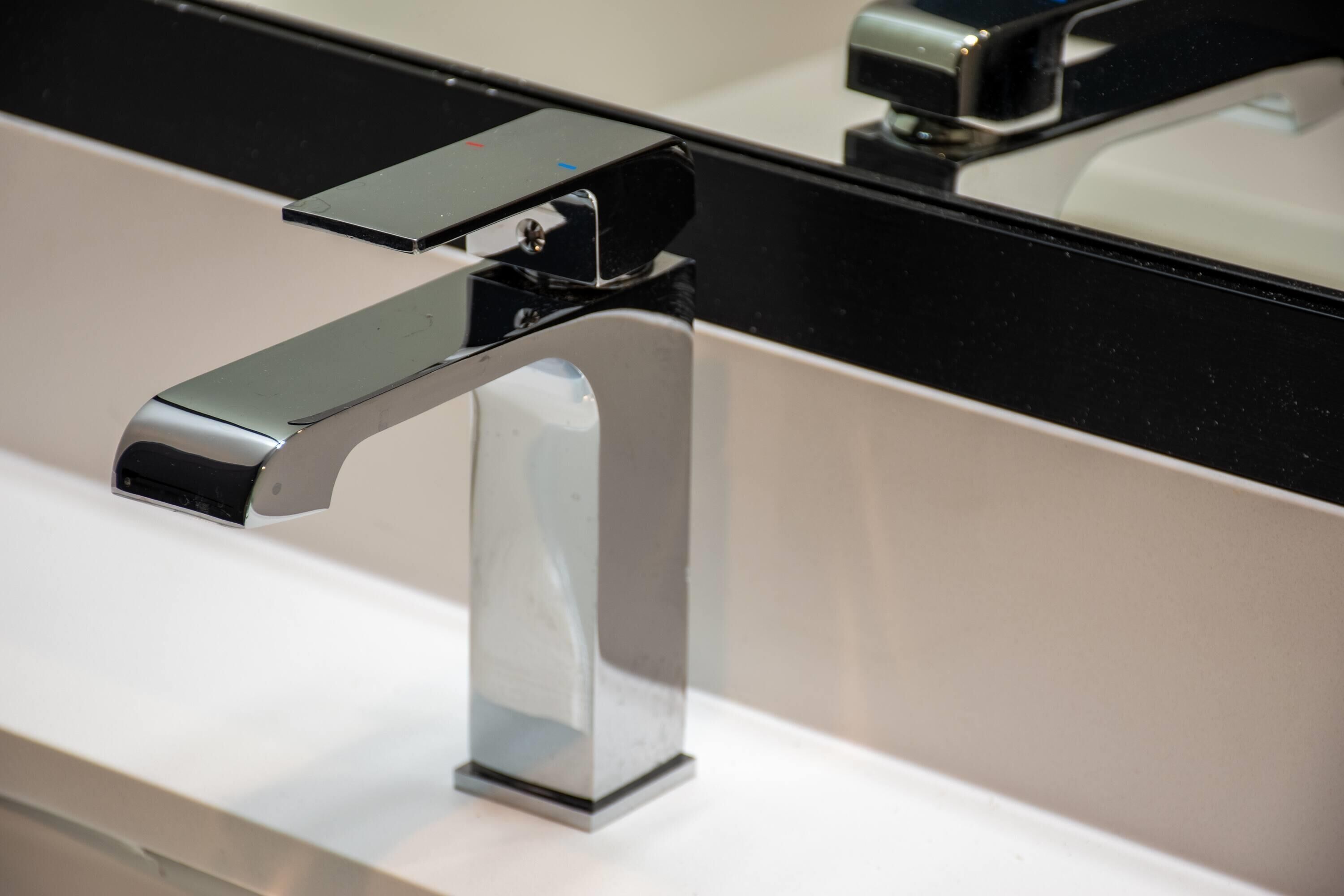 Un baño moderno con grifo cromado y encimera negra.