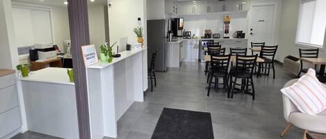 A modern kitchen with white cabinets, a central island, and a dining area with wooden chairs and a table.