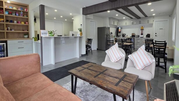 A modern living room with a sofa, a coffee table, and a kitchen area with cabinets and a refrigerator. - Super 8 by Wyndham Clearwater BC (Clearwater)