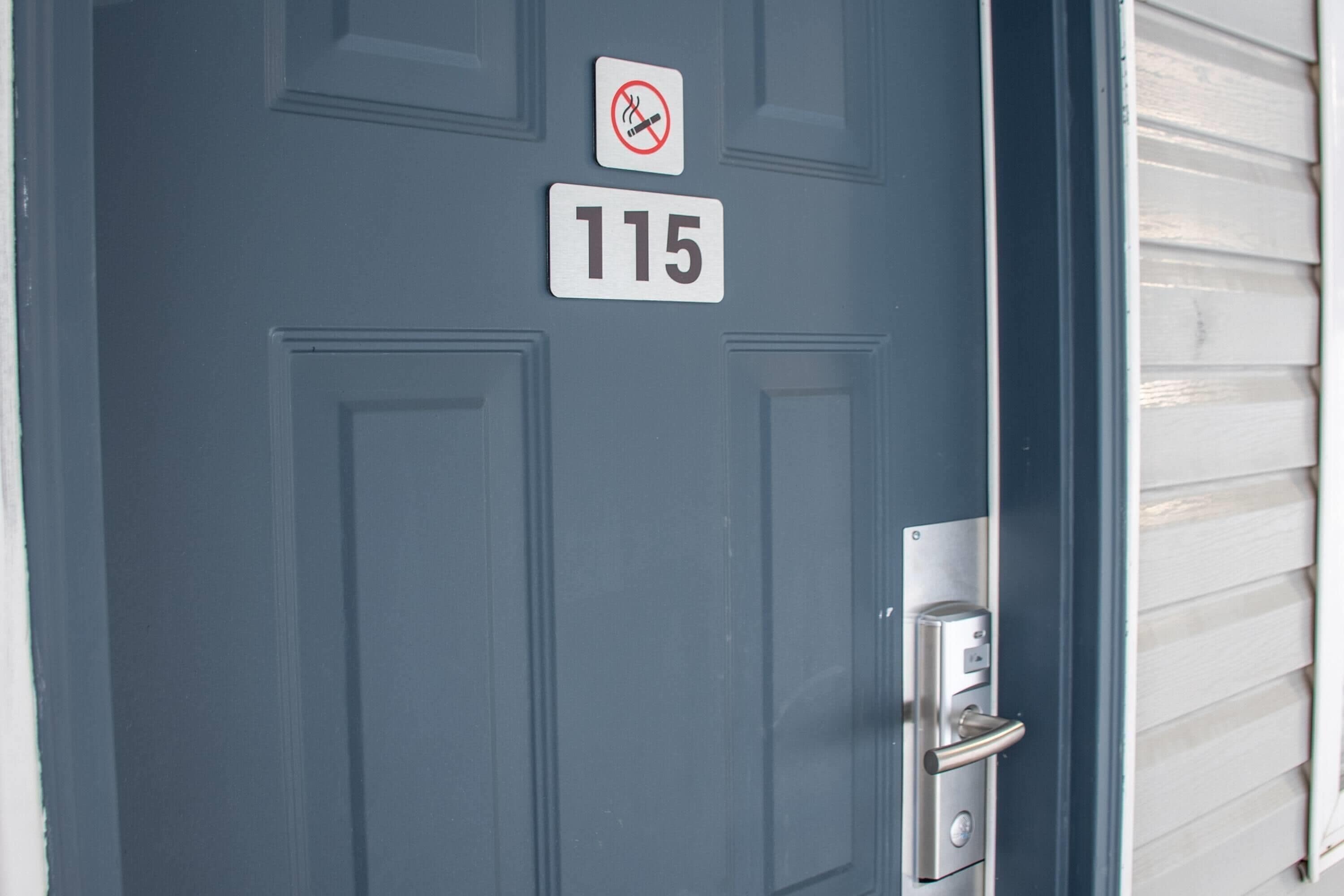 A dark blue door with a '115' sign and a no-smoking symbol above it.