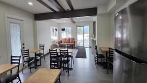 A modern dining area with tables and chairs, a sofa, and a large refrigerator. - Super 8 by Wyndham Clearwater BC (Clearwater)