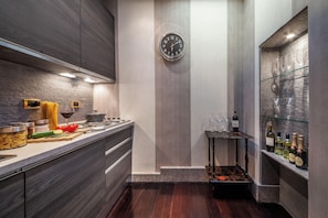 A modern kitchen with a built-in stove, a clock on the wall, and a wine rack with bottles.