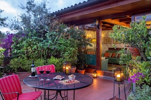 A patio with a round table, red chairs, wine glasses, a bottle of wine, and a candle. - Inn At The Spanish Steps (Rome)