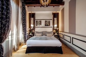 A bedroom with a large bed, two bedside tables, a chandelier, and a view of the city. - Inn At The Spanish Steps (Rome)