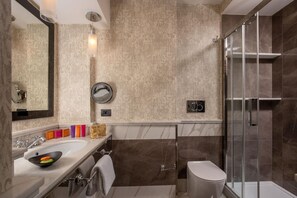 A modern bathroom with a large mirror, a sink with a bowl, a toilet, and a glass-enclosed shower. - Inn At The Spanish Steps (Rome)