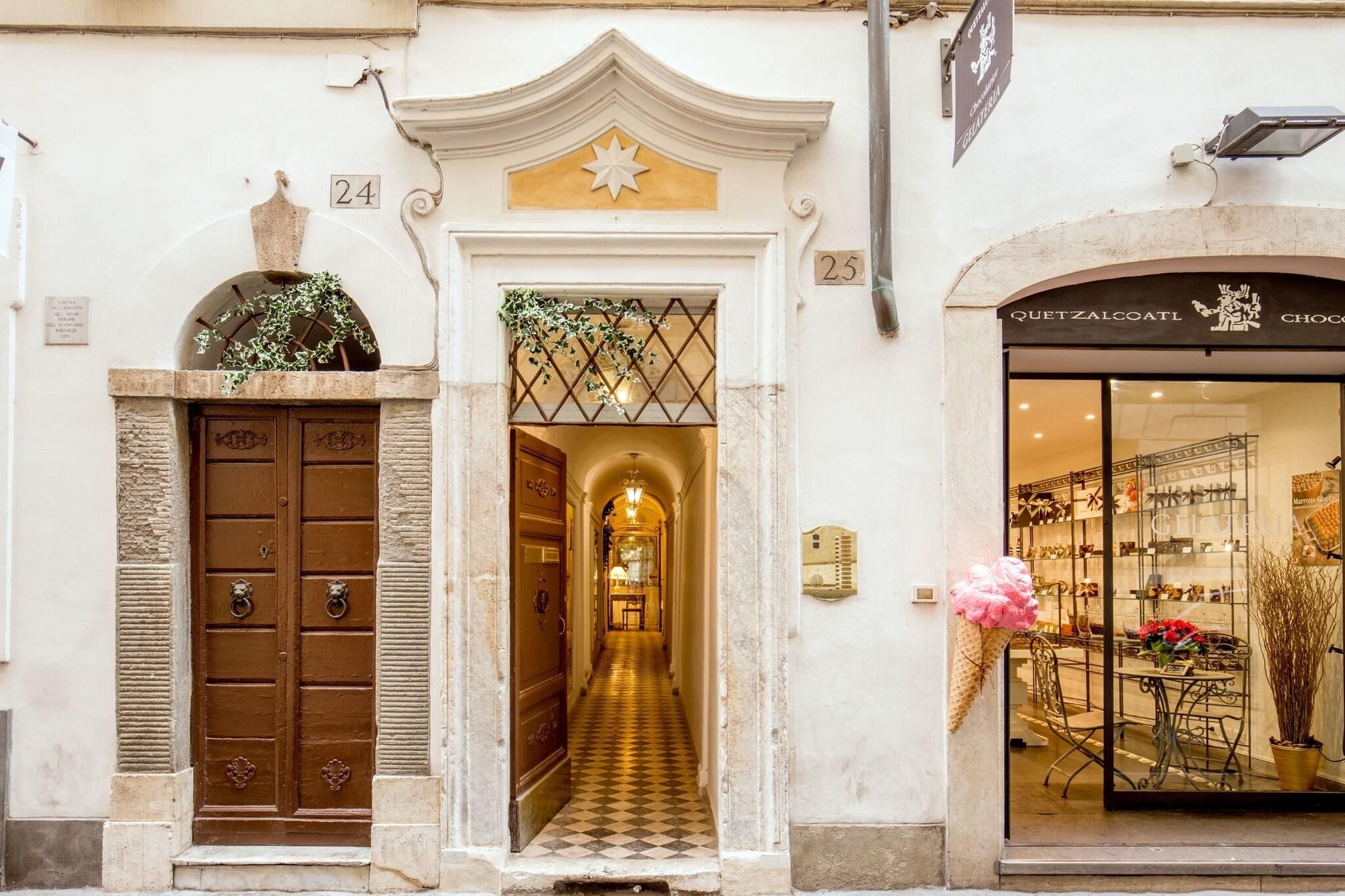 A building entrance with a double door, a hallway leading to a shop, and a sign above the door.