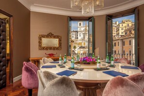A dining area with a round table, chairs, bottles, and a mirror on the wall. - Inn At The Spanish Steps (Rome)