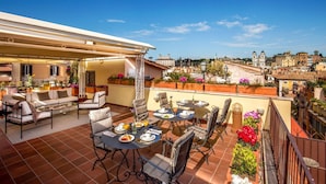 A rooftop terrace with outdoor seating, a dining table set, and a view of the cityscape.