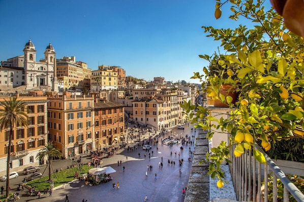 A bustling piazza with historic buildings, a fountain, and a palm tree. - Inn At The Spanish Steps (Rome)