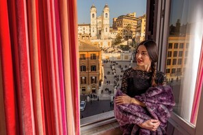 A person standing by a window with a view of a historic building and a staircase. - Inn At The Spanish Steps (Rome)