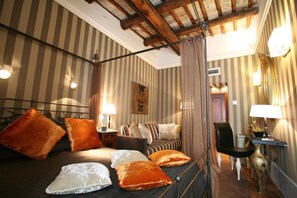 A hotel room with a bed, pillows, a nightstand, a lamp, a chair, a mirror, and a plant. - Inn At The Spanish Steps (Rome)