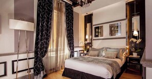 A bedroom with a large bed, bedside tables, lamps, and curtains.
