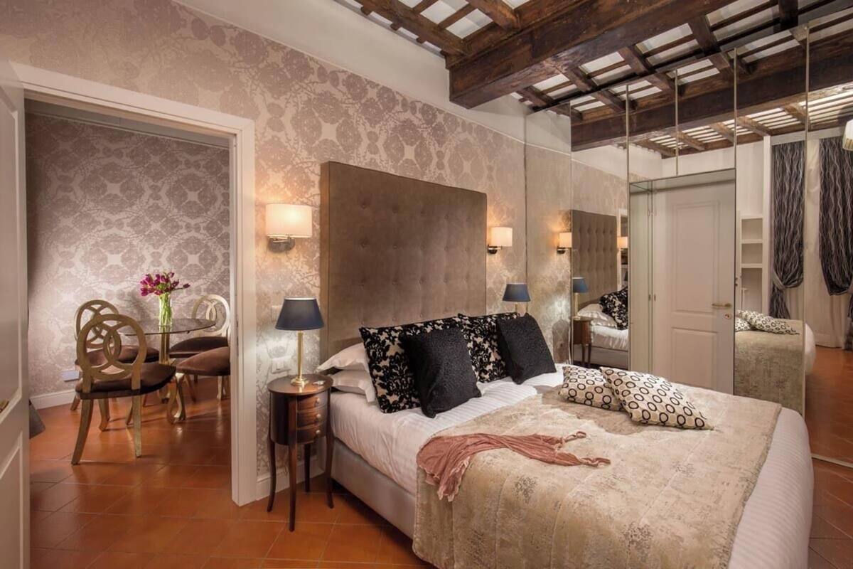 A bedroom with a large bed, a mirror, a small table, and a chair.