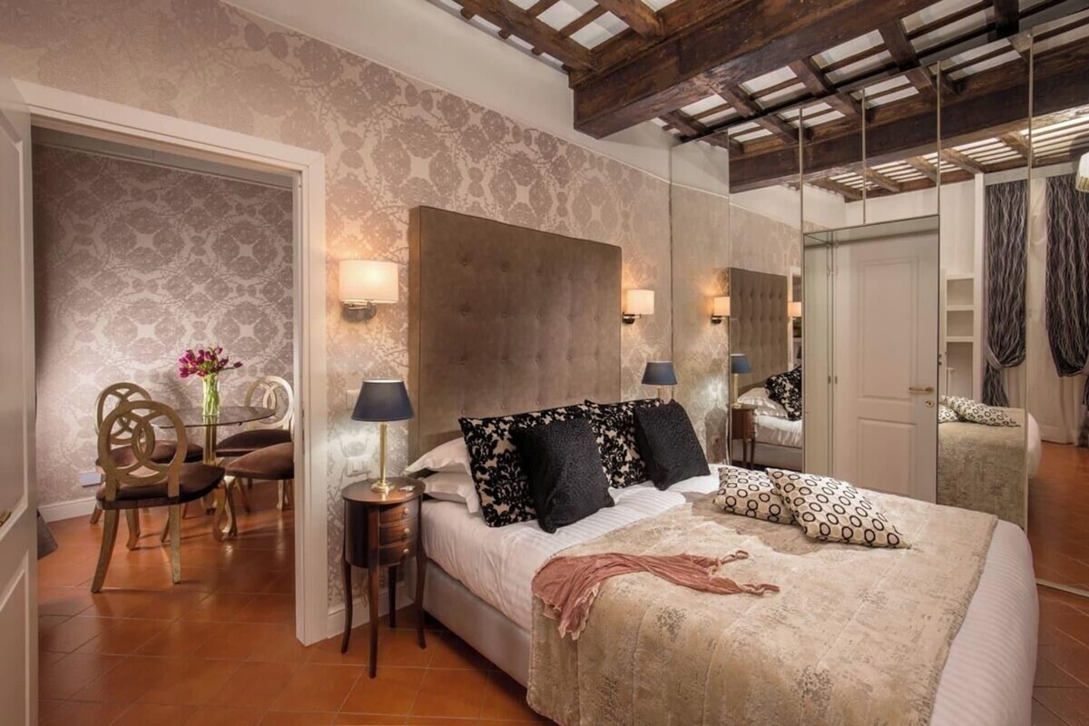 A bedroom with a large bed, a mirror, a small table, and a chair.
