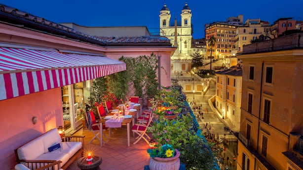 Una terraza en la azotea con mobiliario exterior, una zona de comedor y vistas a una iglesia histórica.