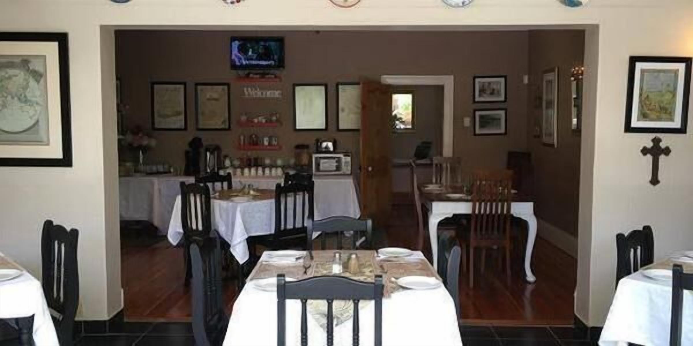 A dining area with tables set for two, chairs, and a television mounted on the wall.