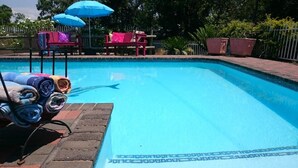 Una piscina con borde de baldosas, rodeada por un deck de ladrillo.