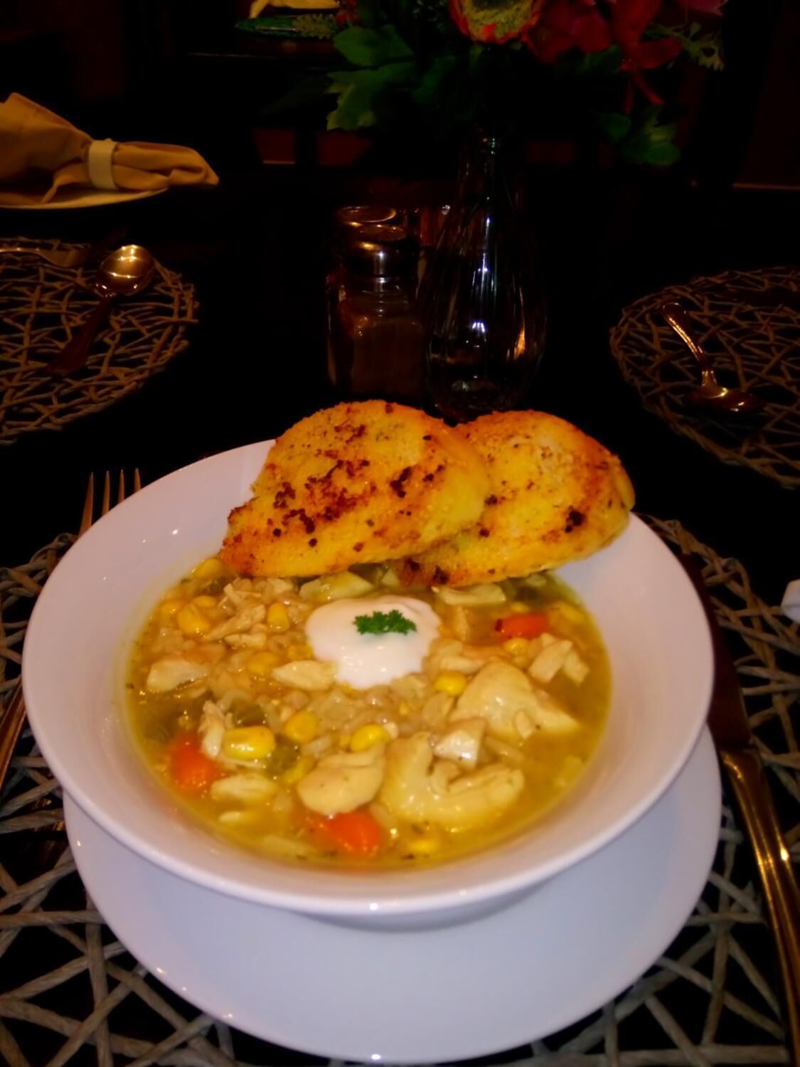 Un tazón de sopa con un huevo poché y una rebanada de pan al lado.