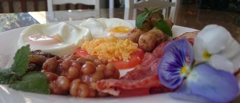 A plate of food with eggs, beans, tomatoes, and bacon.