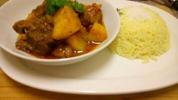Un plato con un guiso de carne y patatas, acompañado de arroz.