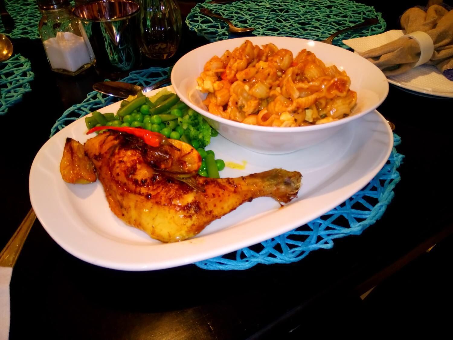 A plate with grilled fish, green beans, and a bowl of pasta.